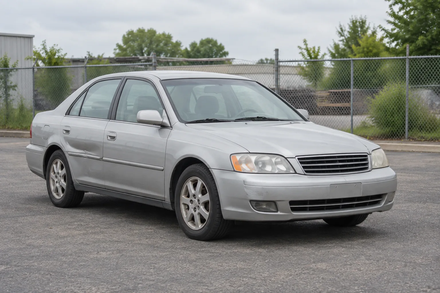 An older silver sedan parked in a yard.